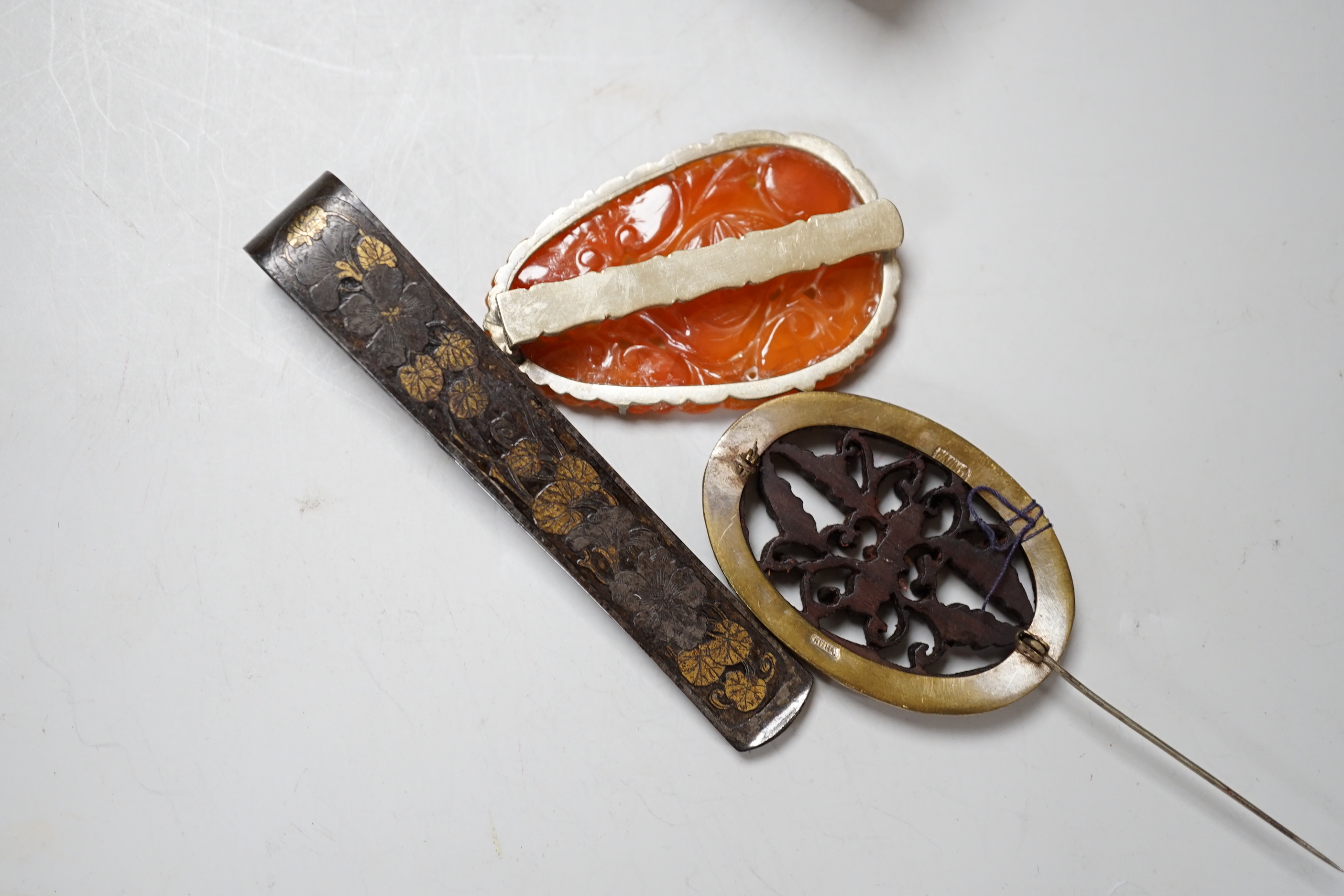 A Chinese chalcedony brooch, a Chinese carved wood brooch, a damascened steel clip and a Japanese trade reference book